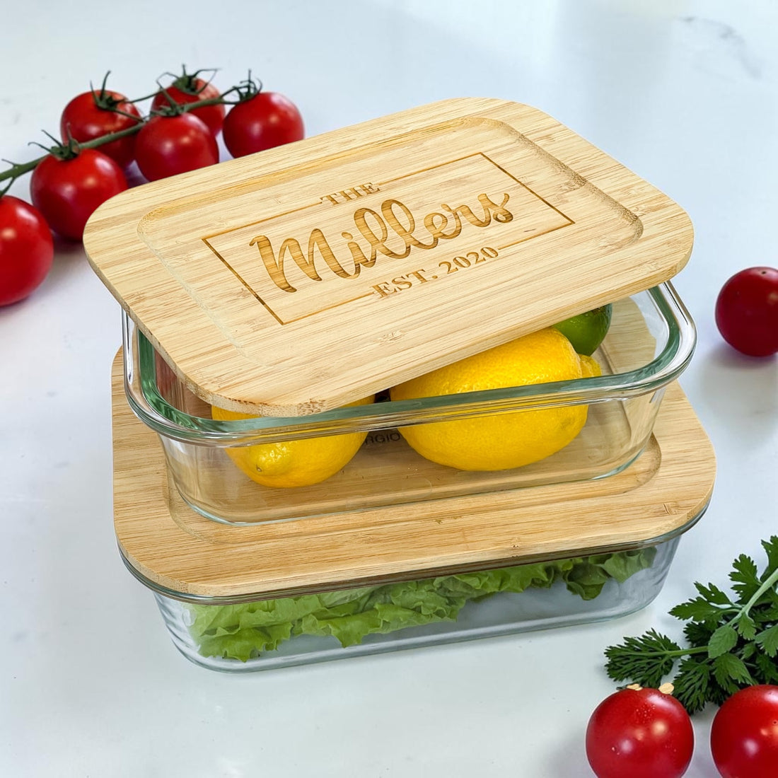 Luxury personalized glass food storage container set with engraved bamboo lids featuring custom family name and established date. Elegant reusable kitchen organization containers styled with fresh produce, lemons, lettuce, and tomatoes for realtor closing gifts, housewarming gifts, and modern kitchen décor.