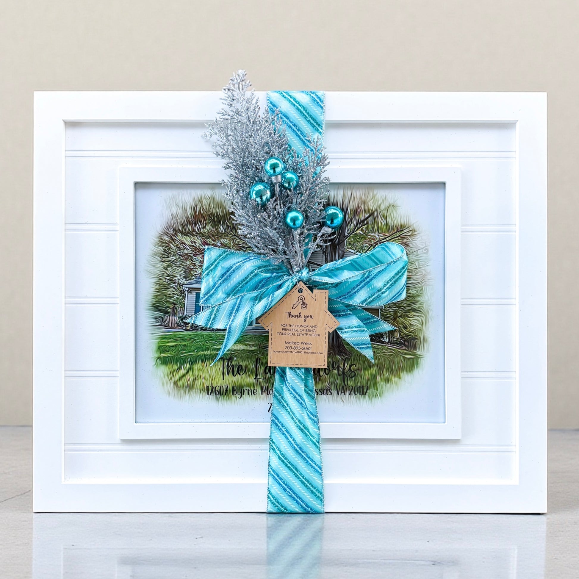Gift wrapped personalized house portrait in white beadboard frame with blue ribbon and realtor thank you gift tag as a luxury realtor closing gift for new homeowners