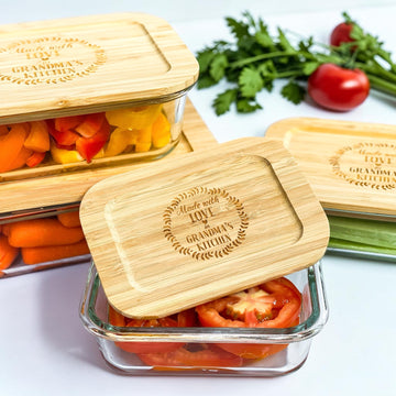 Personalized glass food storage container set with engraved bamboo lids styled with fresh vegetables in a modern kitchen setting. Eco-friendly kitchen organization containers designed for realtor closing gifts, luxury housewarming gifts, and new homeowner gift baskets.