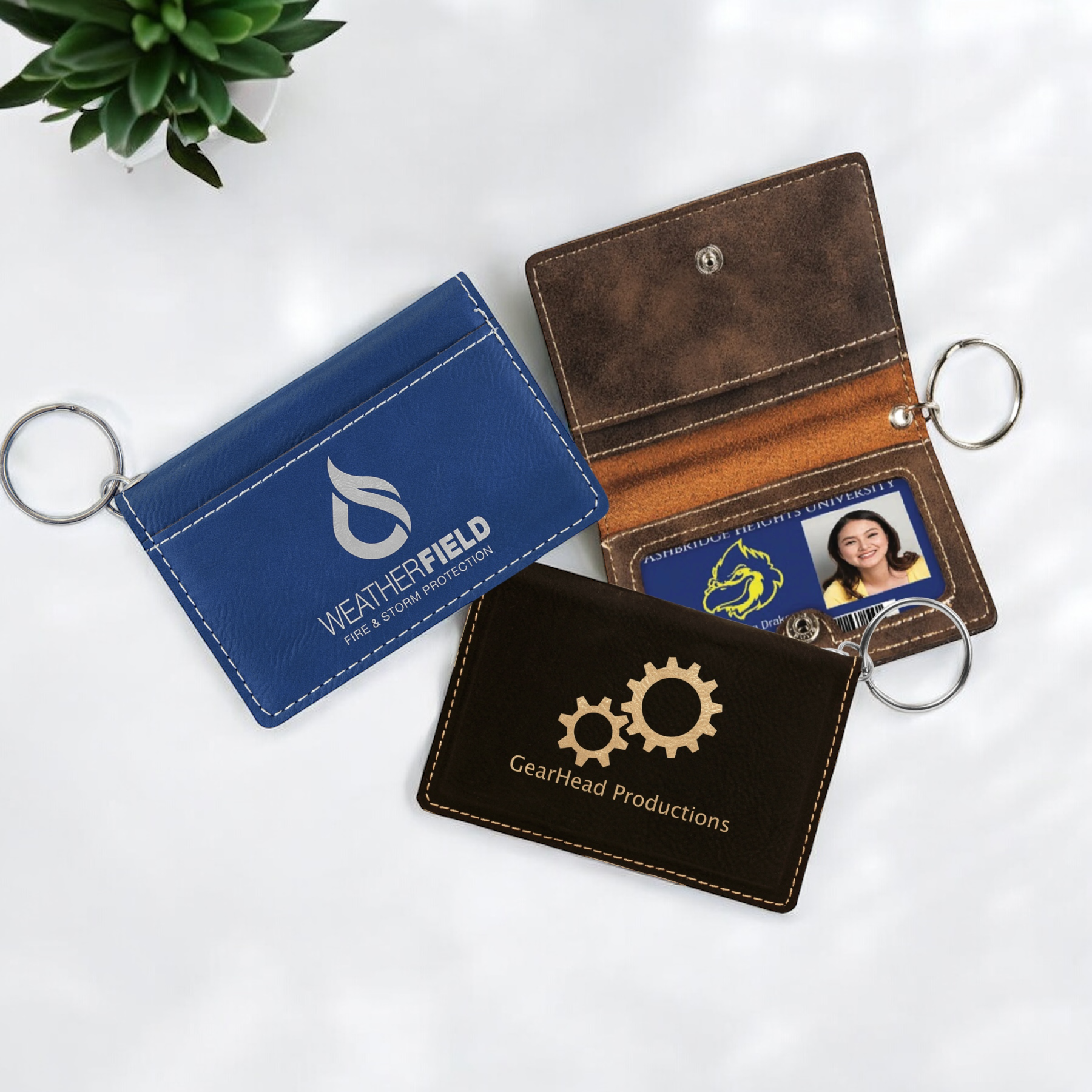 Custom laser-engraved leatherette keychain ID holder with snap closure, exterior pocket, interior card slots, clear ID window, and silver key ring for corporate branding or personalized gifts.