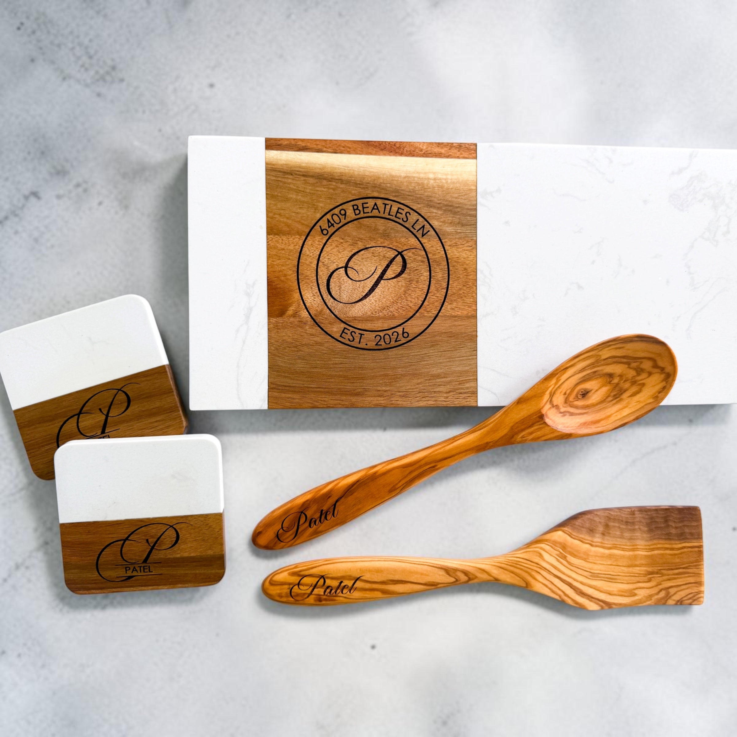 Luxury realtor closing gift set featuring personalized marble and acacia wood charcuterie board, engraved olive wood serving utensils, and matching coasters for home buyers and client appreciation gifting