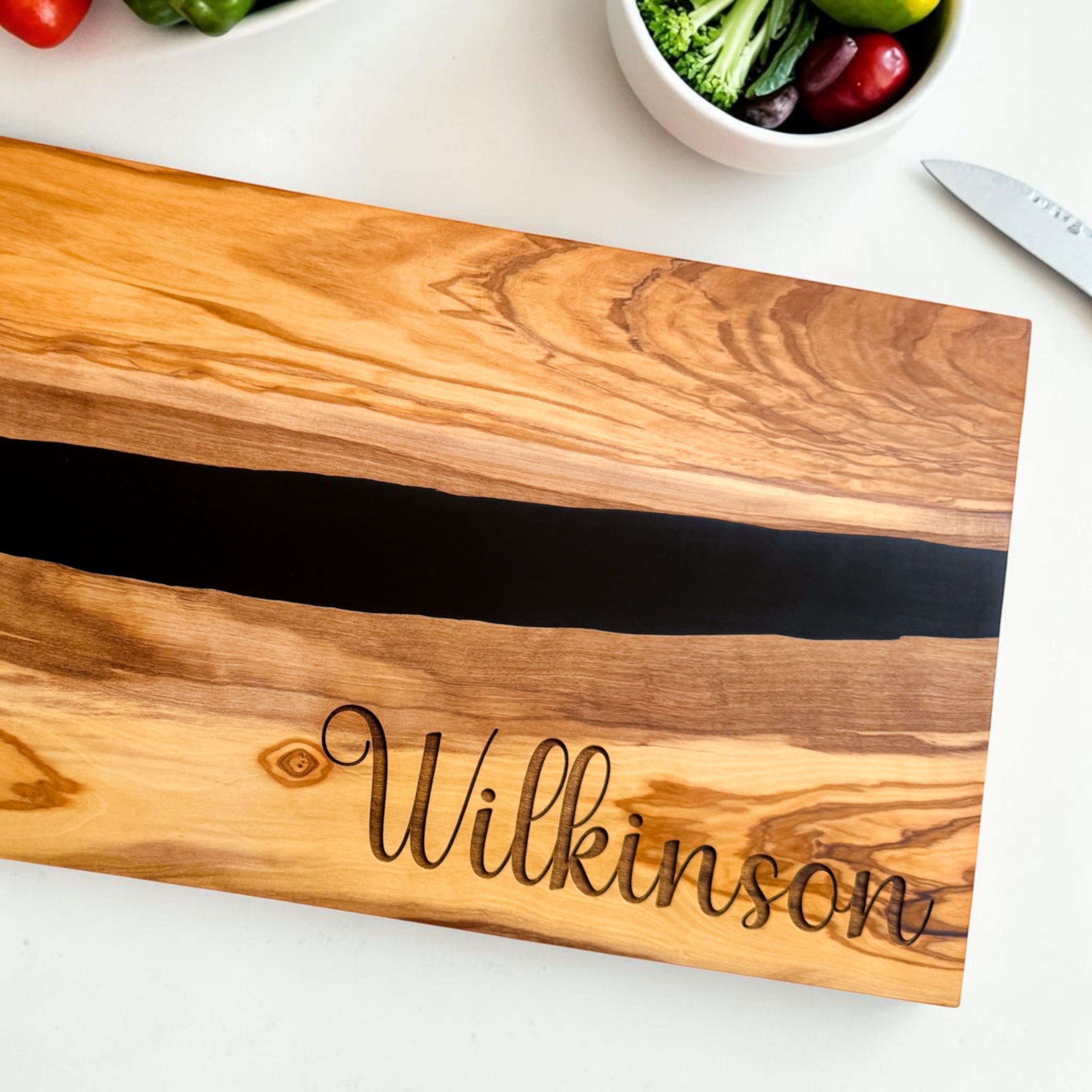 Personalized olive wood and black resin charcuterie board for realtor closing gifts and luxury housewarming gifts styled with engraved utensils and fresh kitchen décor
