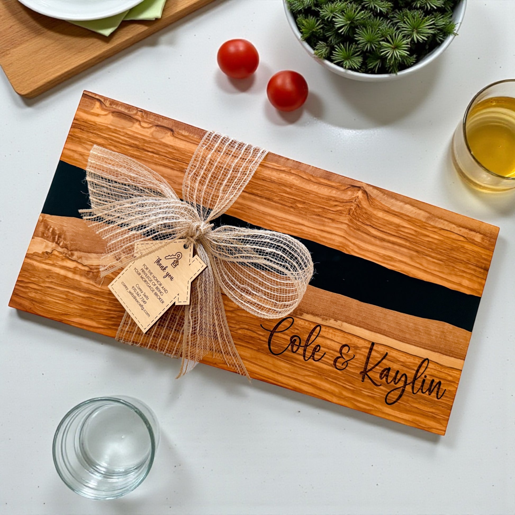 Luxury personalized black river resin and olive wood charcuterie board with engraved names and custom realtor gift tag styled as an upscale closing gift and housewarming present