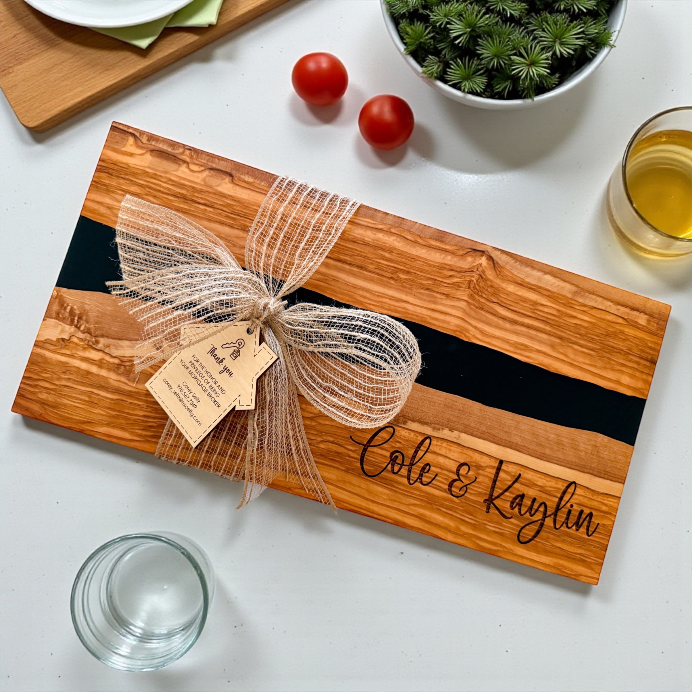 Luxury personalized black river resin and olive wood charcuterie board with engraved names and custom realtor gift tag styled as an upscale closing gift and housewarming present