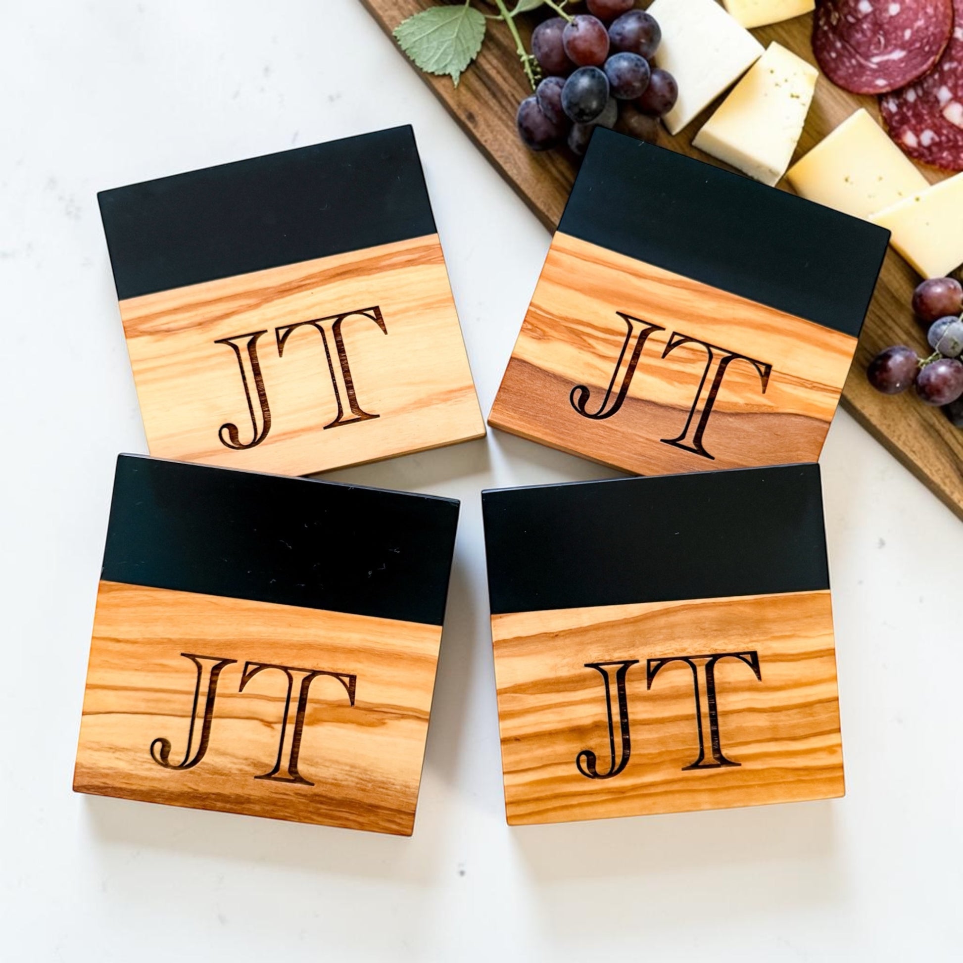 Personalized black river resin and olive wood coaster set with engraved monogram initials styled as a luxury realtor closing gift and modern housewarming kitchen accessory
