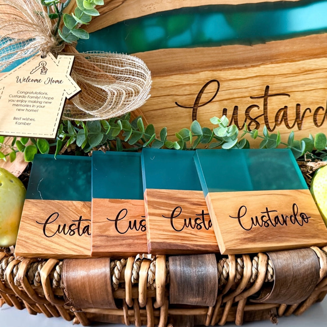 Luxury personalized blue river resin and olive wood cutting board gift basket with engraved coasters, wooden serving spoons, and custom welcome home gift tag designed for realtor closing gifts and upscale housewarming celebrations