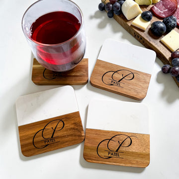 Personalized marble and acacia wood coaster set engraved with monogram and family name styled with wine glass and charcuterie board as a luxury realtor closing gift and housewarming gift