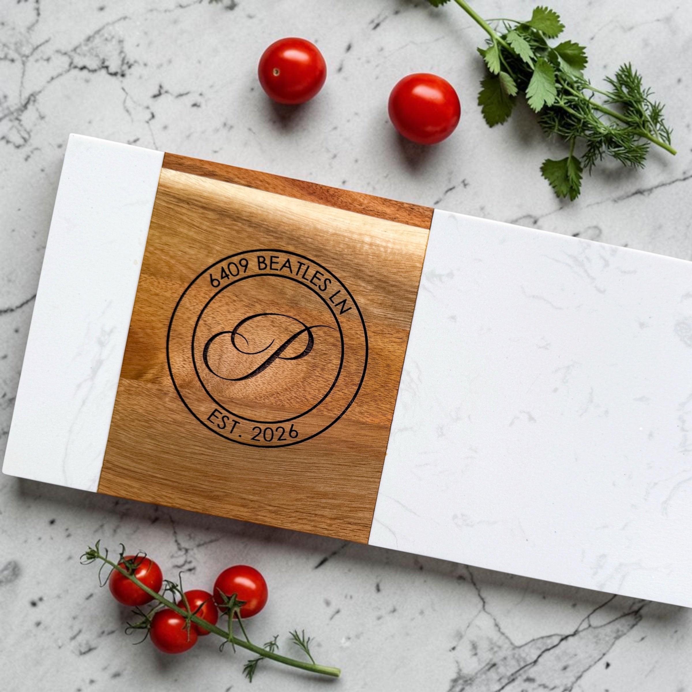 Personalized marble and acacia wood serving board engraved with monogram and address styled with fresh tomatoes and herbs as a luxury housewarming gift and realtor closing gift