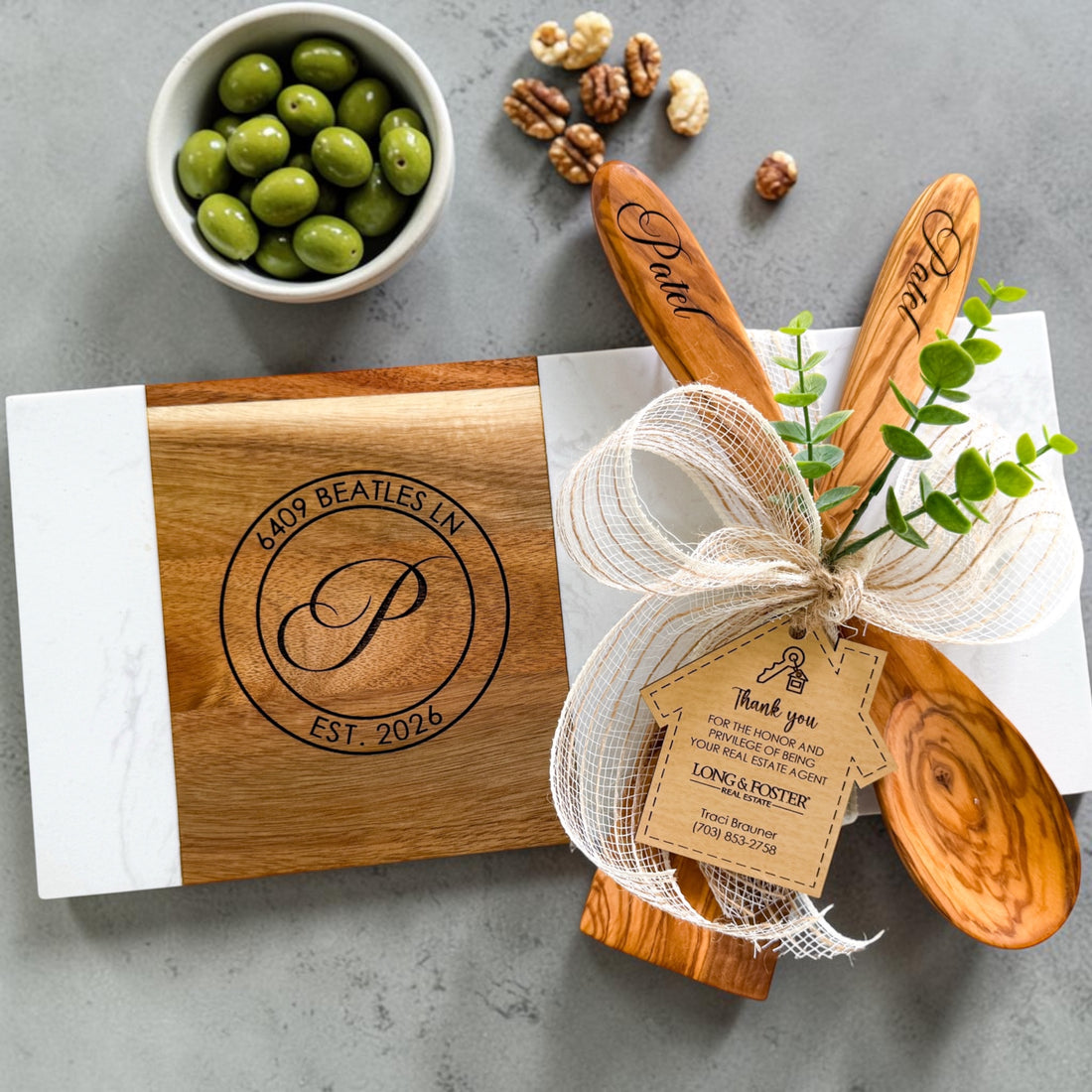 Modern personalized marble and acacia wood charcuterie board engraved with monogram, address, and established date styled on neutral kitchen background for realtor closing gifts and new homeowners